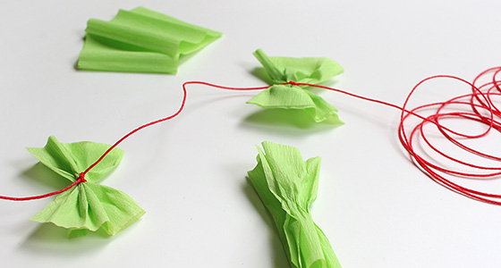 Schleifen aus Krepppapier mit rotem Faden